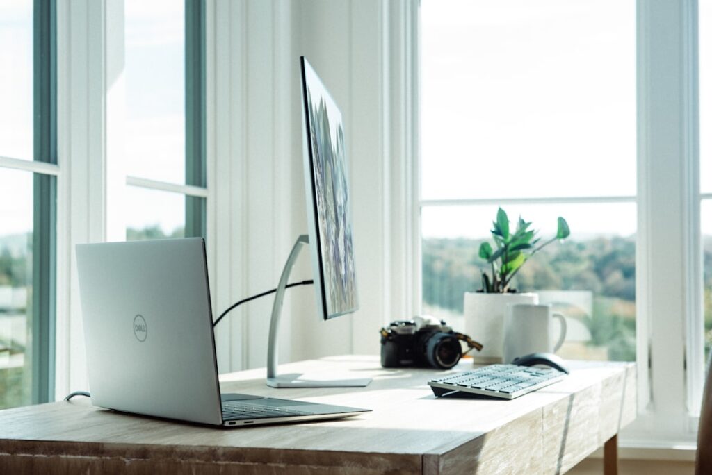 A neatly organized desk with a laptop, a pen holder, and a few carefully arranged office supplies. The lighting is soft and diffused, creating a warm, productive atmosphere. In the background, a bookshelf with a few plants and decorative items adds visual interest. The overall scene conveys a sense of progress and the evolving nature of a workspace, reflecting the section's theme of "Progress Over Perfection: Building Lasting Habits". silver laptop on white table